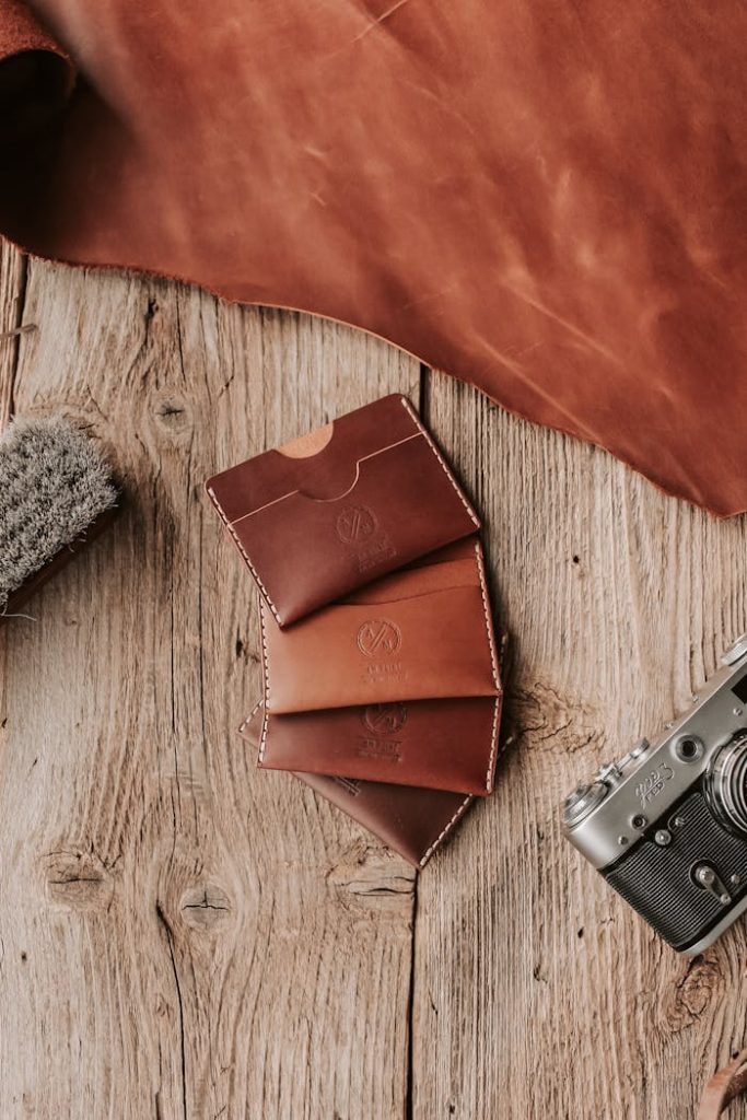 Brown Leather Card Holders and a Sheet of Leather Lying on a Wooden Surface